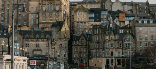 A view from Princes Street looking across Waverley Bridge towards Edinburgh Old Town. The image is displayed in landscape orientation, taking up the full width of the page with no cropping of the original image.