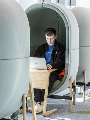 A male student works from his laptop in a one-person study pod.